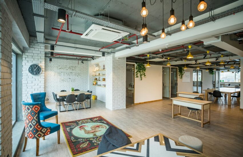 Ein moderner Coworking-Space mit Beleuchtung im Industrial-Stil, Sesseln, Tischen und Stühlen